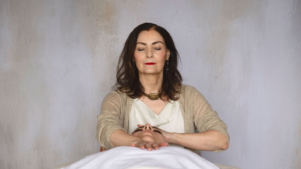 Monica meditating with closed eyes against a plain background